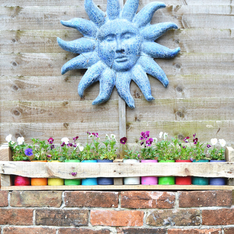Upcycled colorful tin can planters with a handy pallet trough.