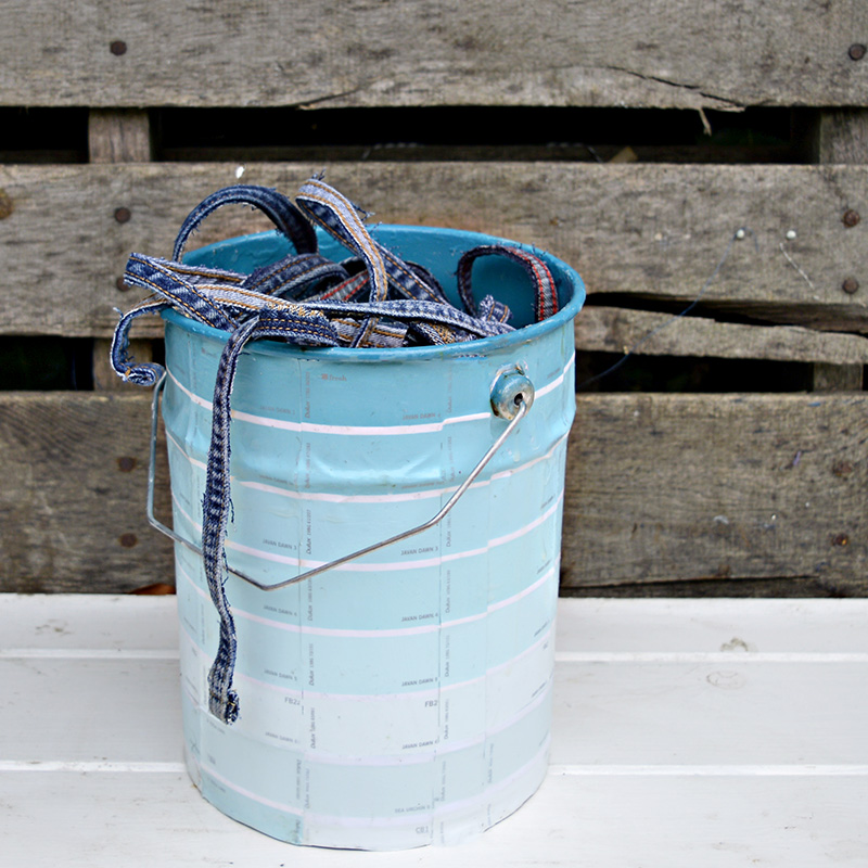 Empty paint cans upcycled with paint chips for colourful storage or planters.