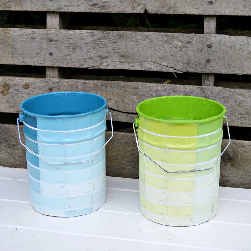Empty paint cans upcycled with paint chips for colourful storage or planters.
