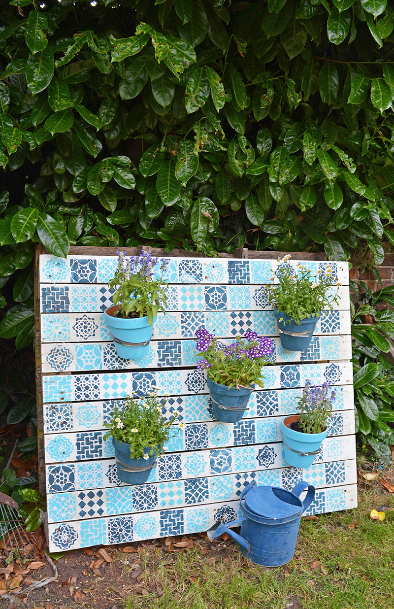Upcycle an old wood pallet with a Moroccan tile stencils, to make an bright painted wood pallet wall planter to add colour to your garden.