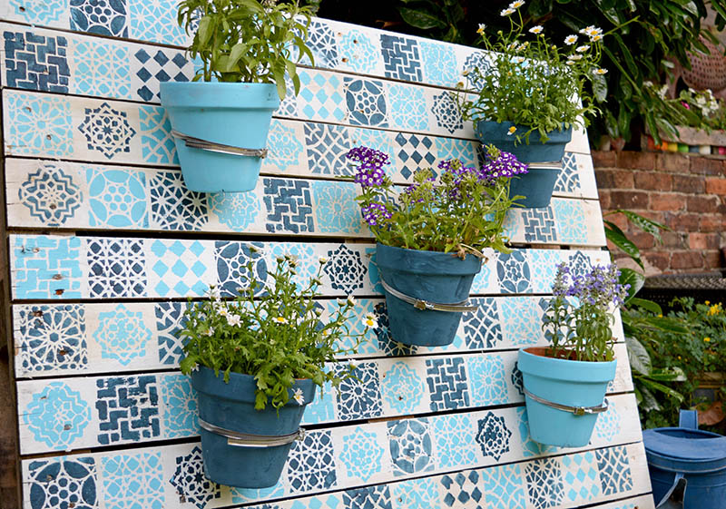Upcycle an old wood pallet with a moroccan tile stencils, to make an bright painted wood pallet wall planter to add colour to your garden.