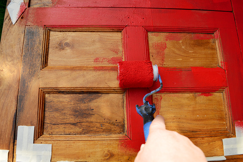 Painting a cabinet with a mini roller and chalk paint.