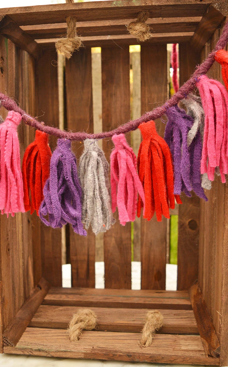 Repurpose sweater scraps into fun felt tassels. They make a lovely keychain or a gorgeous gift topper. Make a few and hang them into a lovely garland. #feltgarland #felt #sweaterupcycle #tassel #felttassel