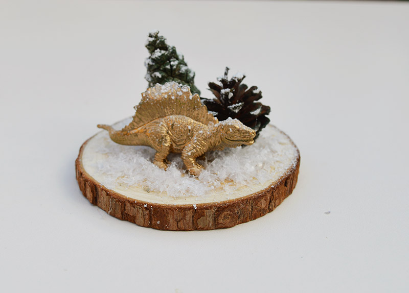 Glueing dinosaur and tree to woodslice for Christmas dinosaur terrarium