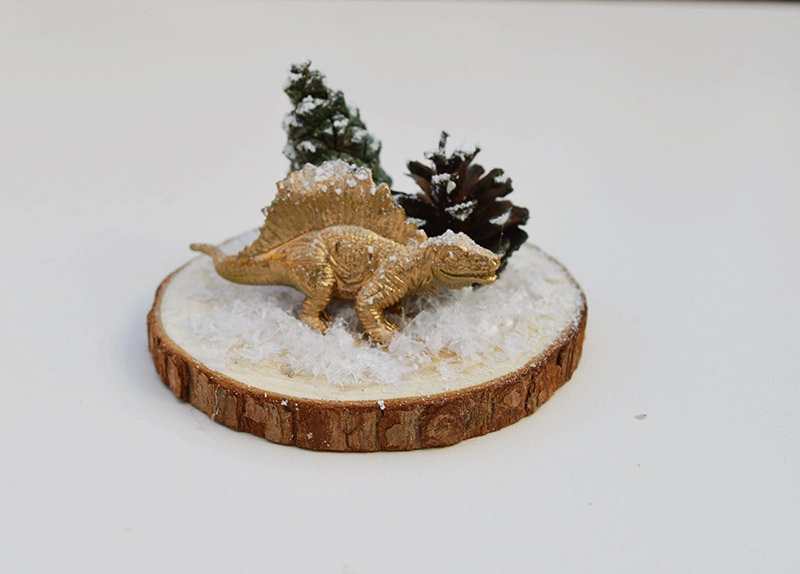Glueing dinosaur and tree to woodslice for Christmas dinosaur terrarium