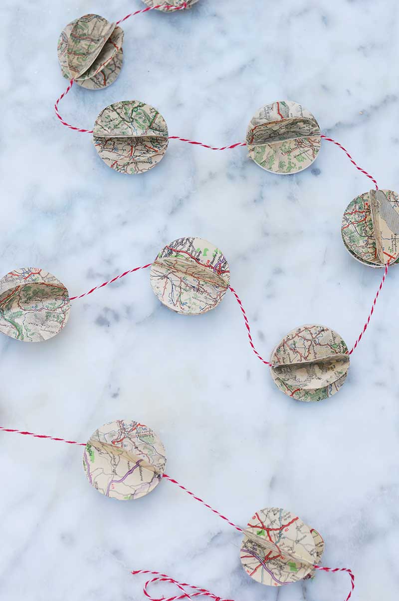 41 Easy Christmas Paper Crafts to Make for the Holidays: Upcycle old road maps to make a gorgeous DIY map decorations in the form of a garland.