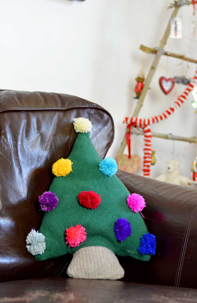 Christmas tree pillow made from old sweaters with pom pom decorations