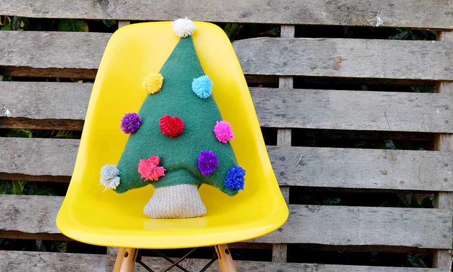 Repurpose an old sweater into a cute Christmas tree pillow with pom pom decorations