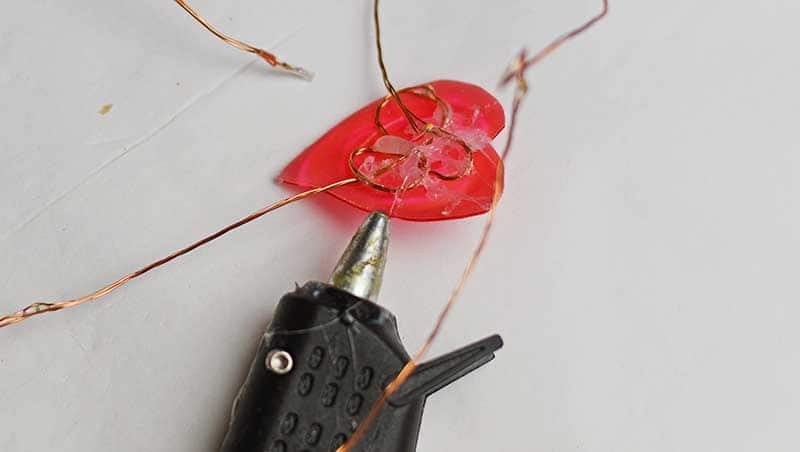 Gluing copper wire lights to the back of plastic hearts