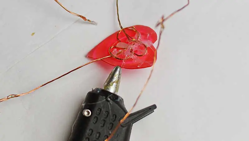 Gluing copper wire lights to the back of plastic hearts