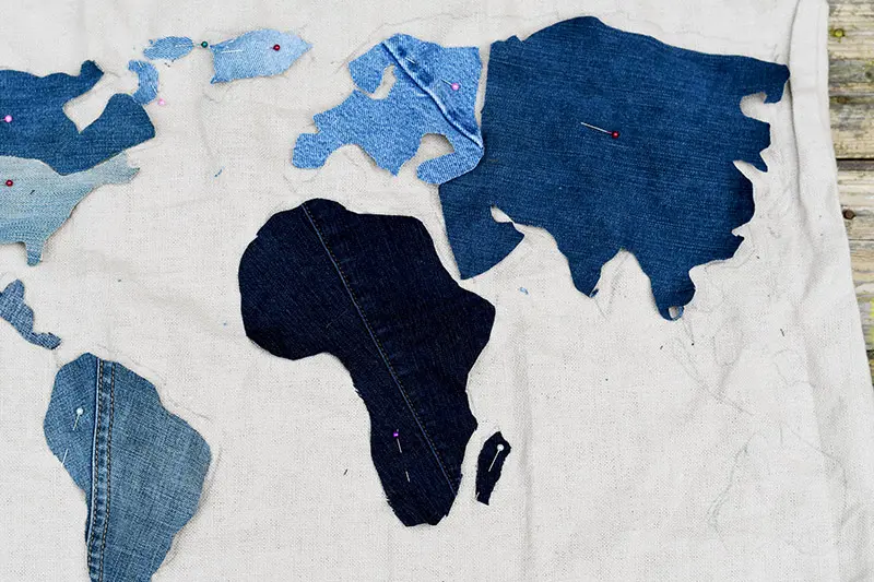 Pinning denim pieces to world map floor cushion