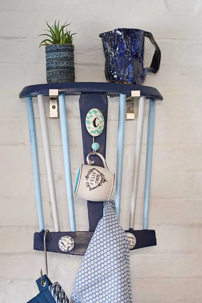 Repurposed Chair back into a handy kitchen towel rack and storage.