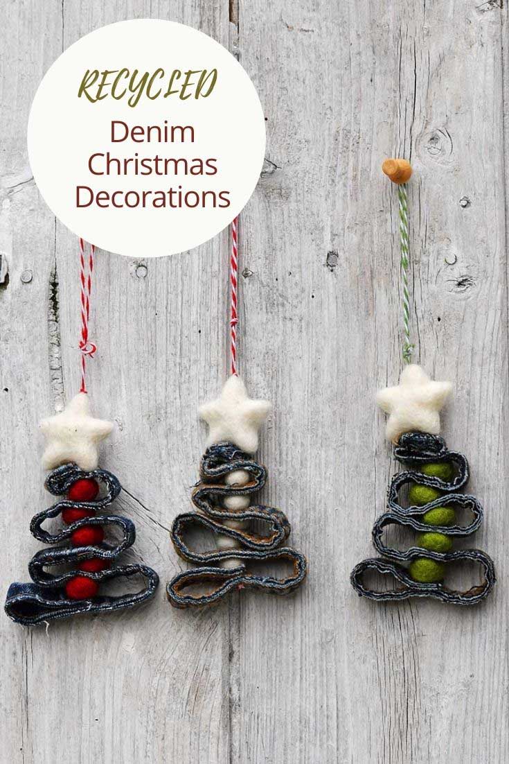 Three Christmas tree ornaments made from zigzagged denim seams with colorful felt balls and white felt stars on white wood