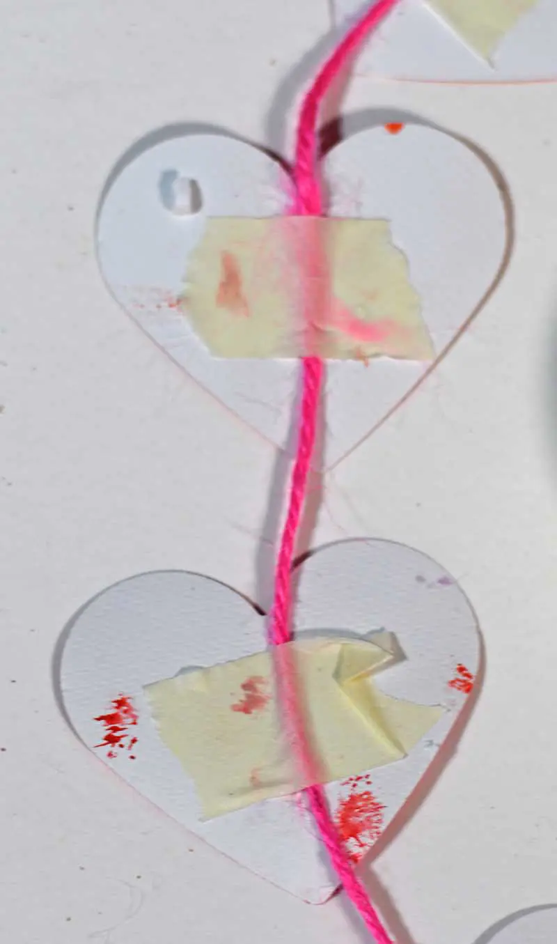 Fixing hearts to twine with masking tape