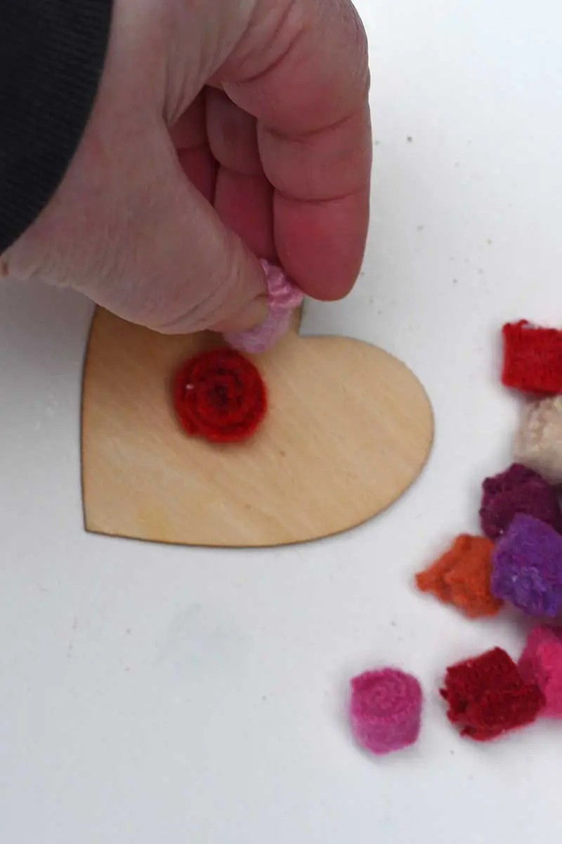 Gluing the felt flowers to the wooden hearts