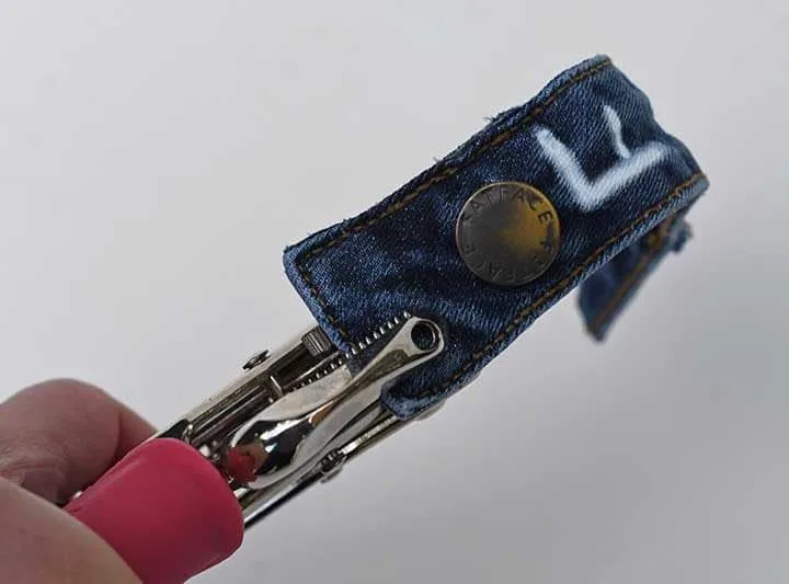 Punching holes in the denim waistband.