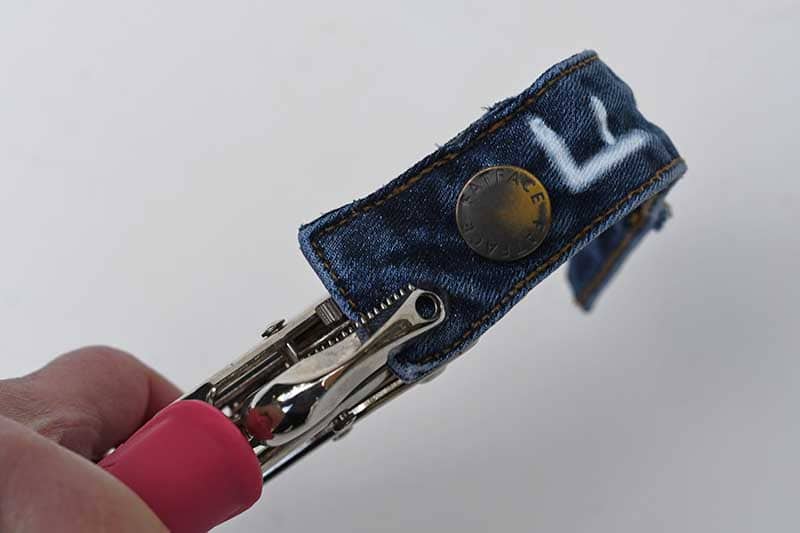 Punching holes in the denim waistband.