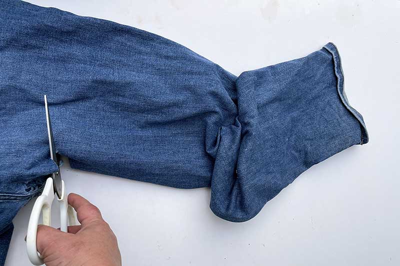 cutting the leg off a pair of jeans