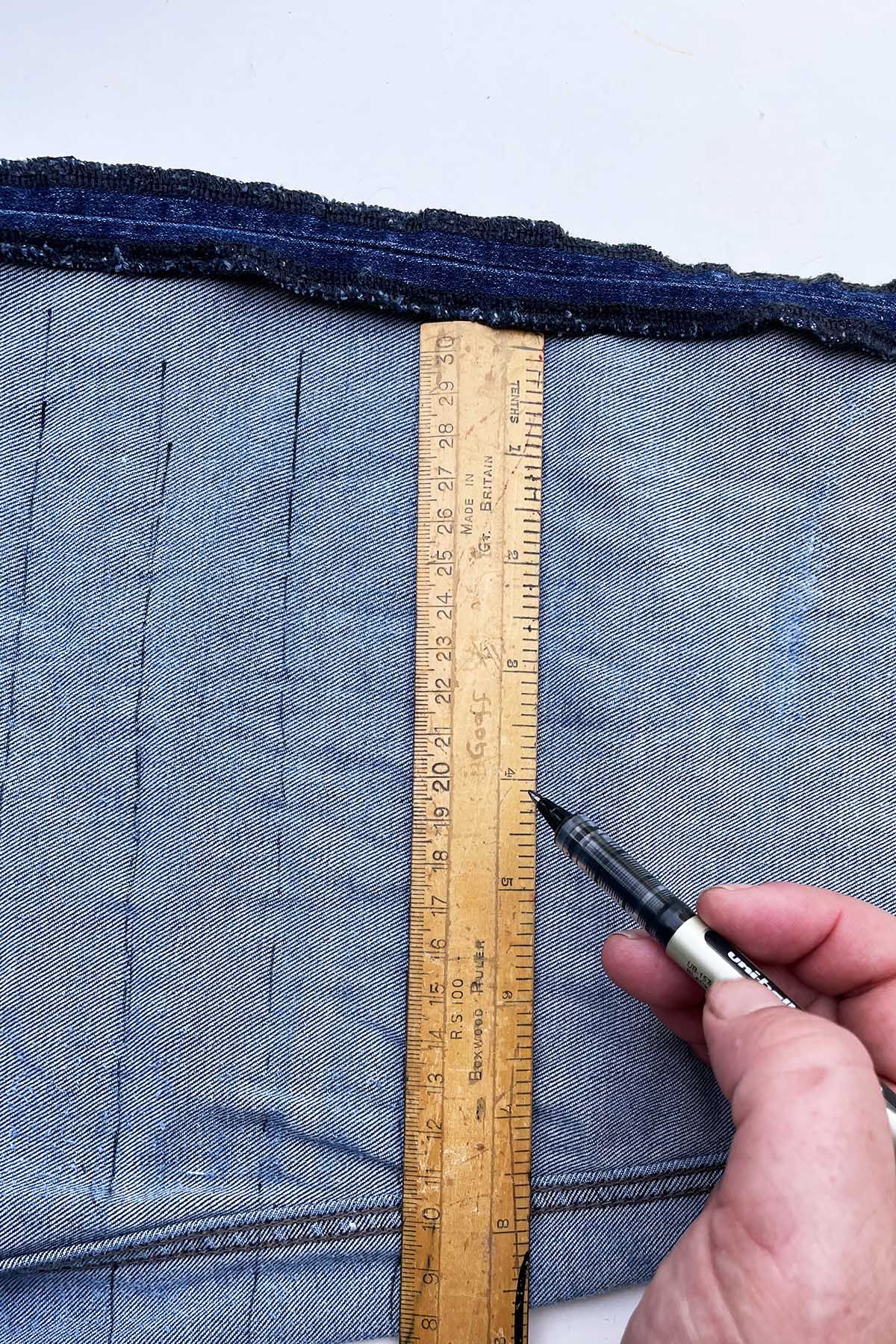Marking the cut lines on a leg of jeans with pen and ruler