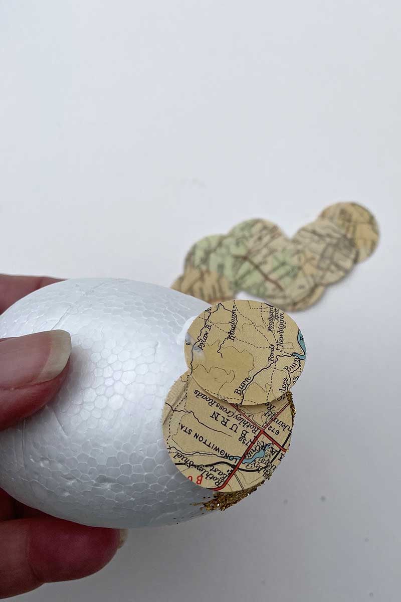 Gluing map paper circles to polystyrene egg.