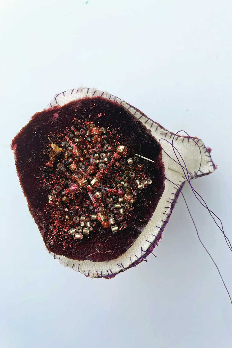 stitching seeds to front of fabric fig ornament