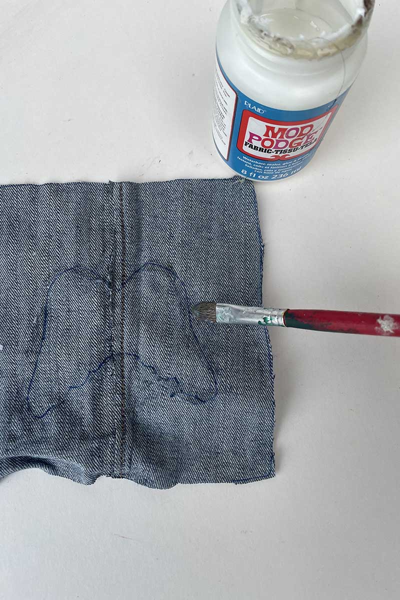 Dabbing glue around Christmas outline shape on denim