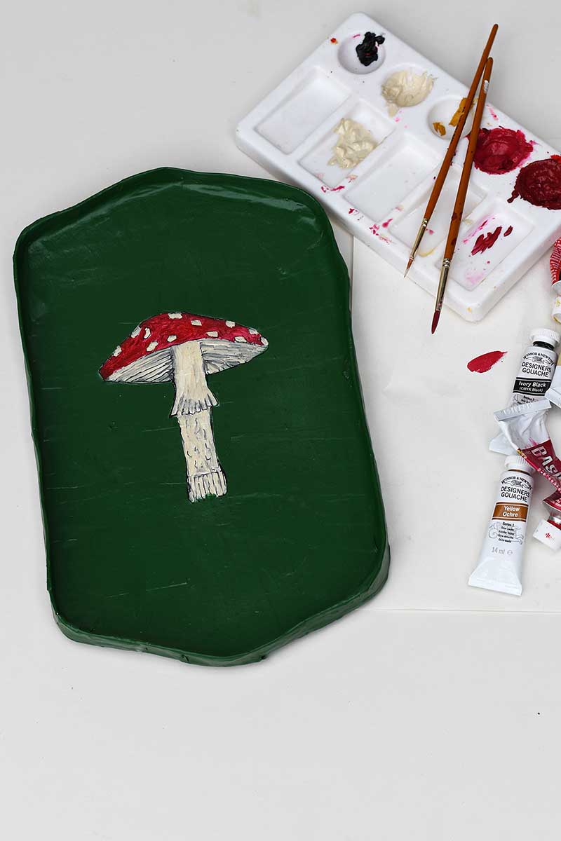Painting a hand drawn mushroom onto a paper mache tray