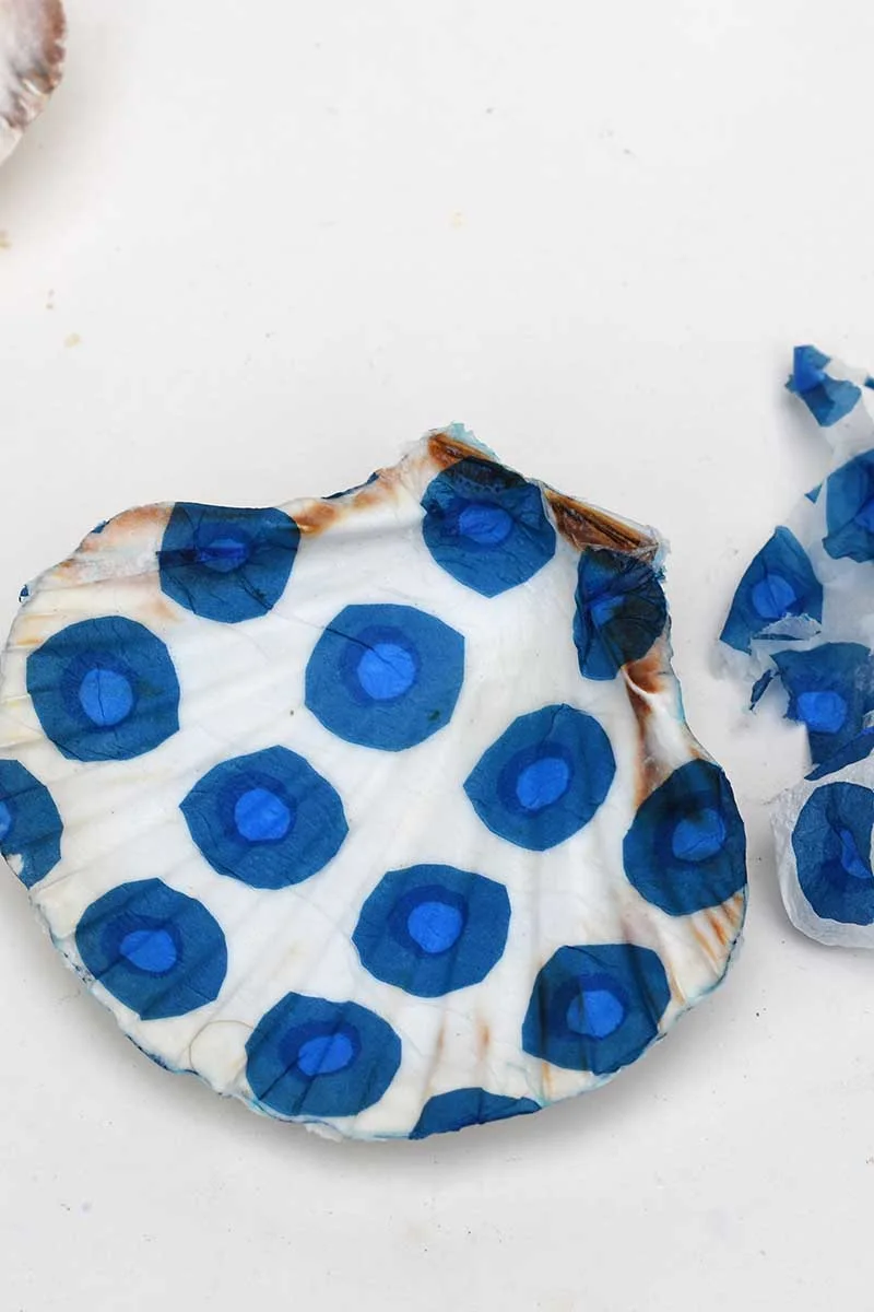 Tearing away excess paper napkin from the decoupaged scallop shells