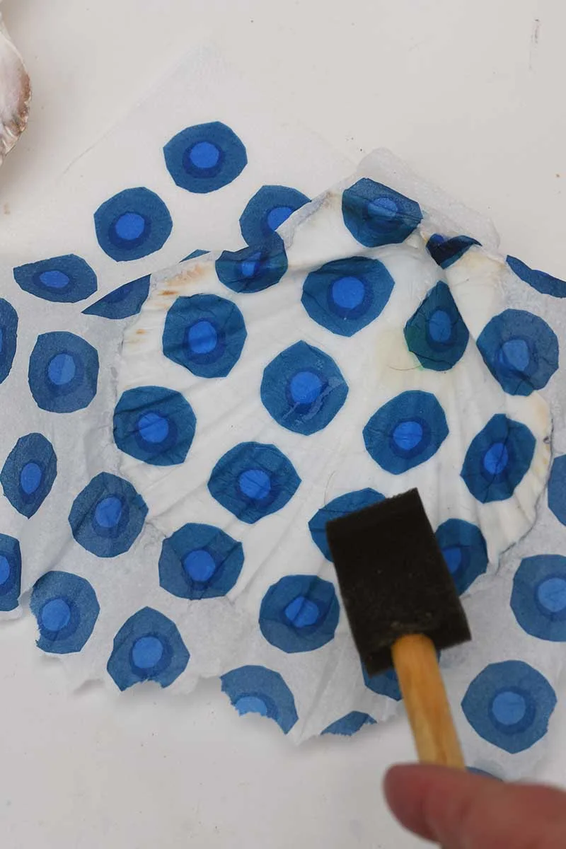 Decoupaging scallop shells inside with paper napkins and foam brush