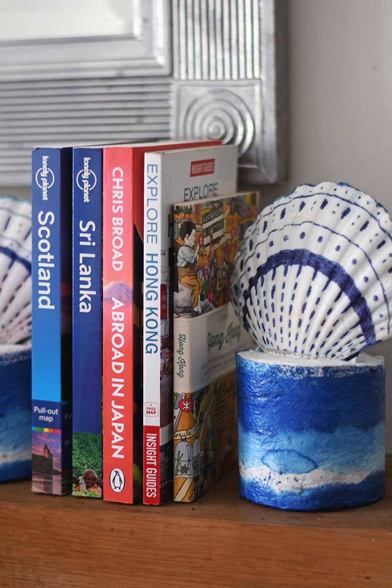 diy scallop shell bookends on the mantle with travel themed books