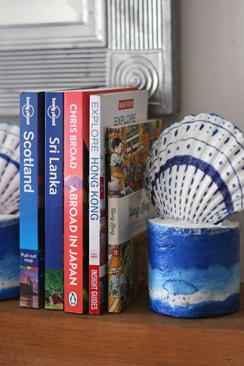 diy scallop shell bookends on the mantle with travel themed books