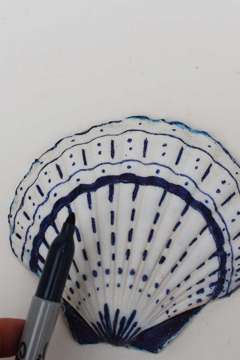 Decorating the back of a scallop shell with a blue  Sharpie pen