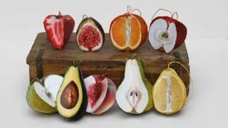 3d paper fruit ornaments including peach, pear, strawberry, green apple, red apple, fig, lemon, orange and avocado on a wooden box