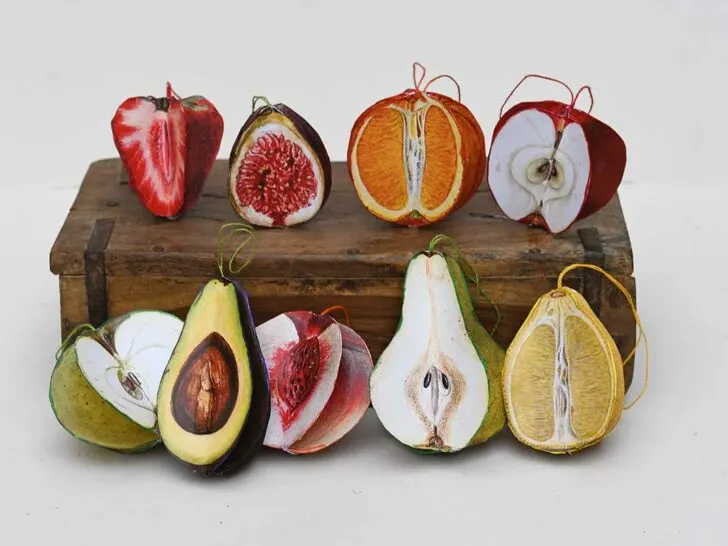 3d paper fruit ornaments including peach, pear, strawberry, green apple, red apple, fig, lemon, orange and avocado on a wooden box