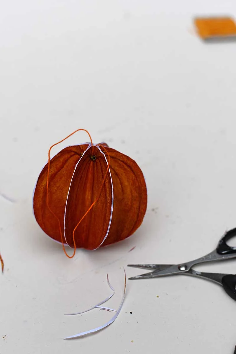 Trimming the edges of the orange ornament with scissors