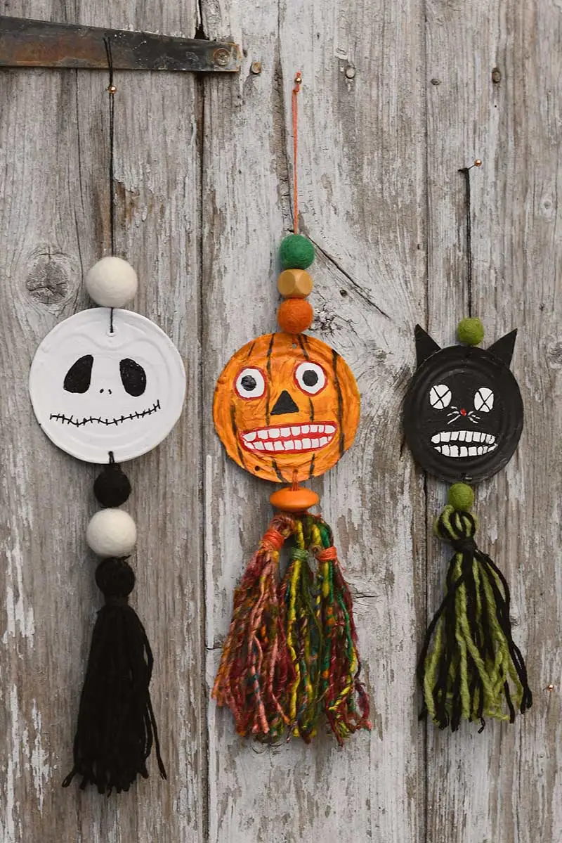 All three hanging spooky upcycled tin can Halloween faces decorations hanging on wood