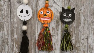 All three hanging spooky upcycled tin can Halloween faces decorations hanging on wood