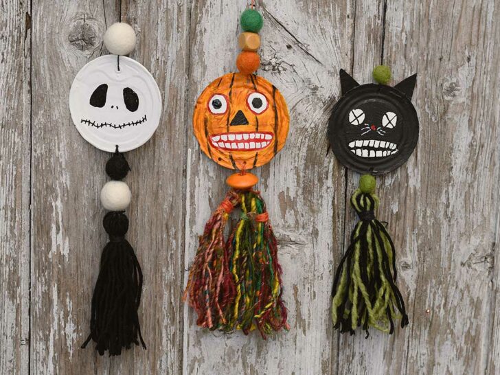 All three hanging spooky upcycled tin can Halloween faces decorations hanging on wood