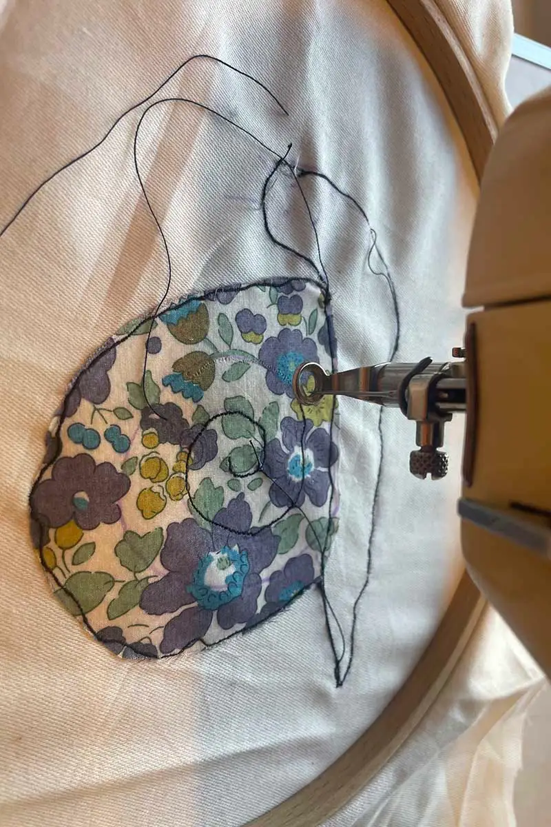 free motion embroidery of applique snail with a sewing machine showing the black stitching. 