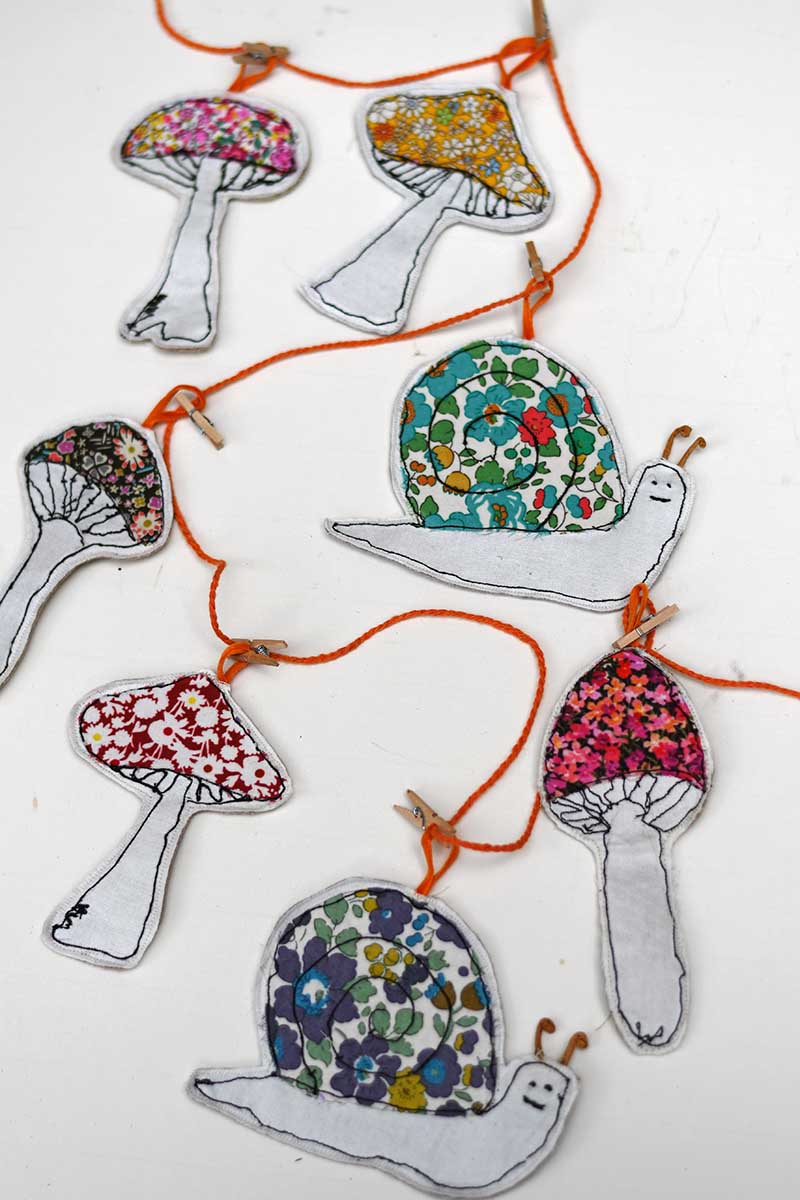 garland of mushroom and snail ornaments made with free motion embroidery and applique fabric scraps