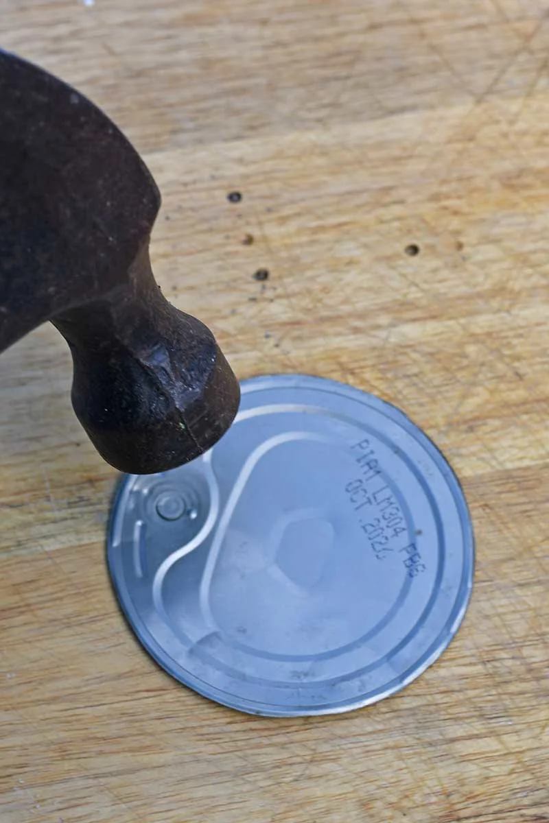 Hammering the tin can lids for upcycled Halloween decorations