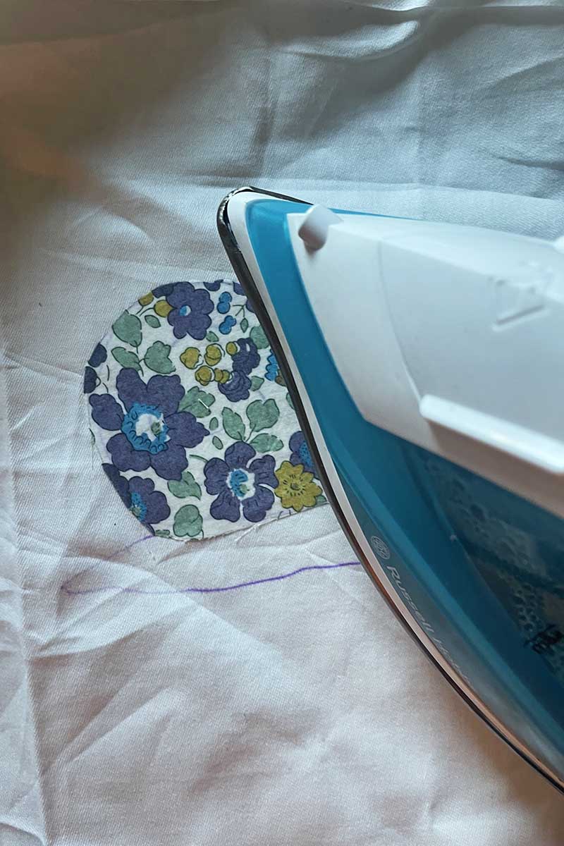 ironing on scrap liberty fabric onto bed sheet on snail pattern for free motion embroidery applique craft