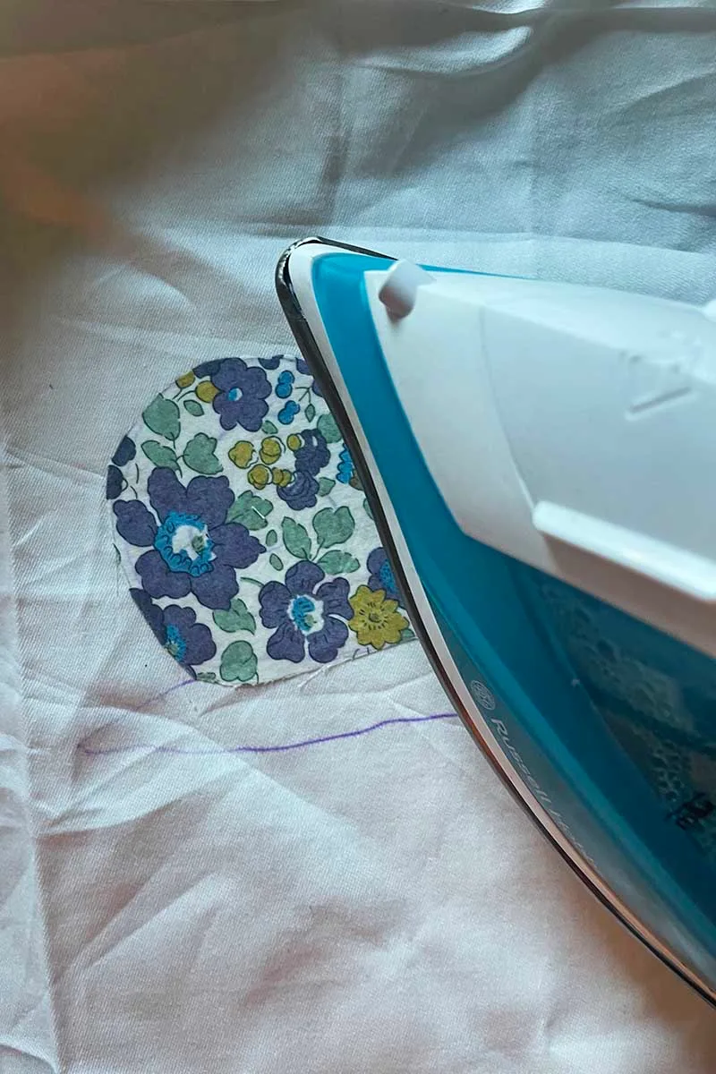 ironing on scrap liberty fabric onto bed sheet on snail pattern for free motion embroidery applique craft