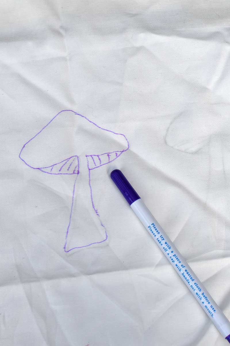 Drawing around mushroom template on cotton fabric with water soluble pen.