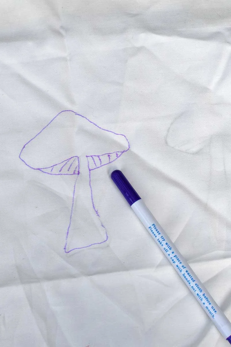Drawing around mushroom template on cotton fabric with water soluble pen.