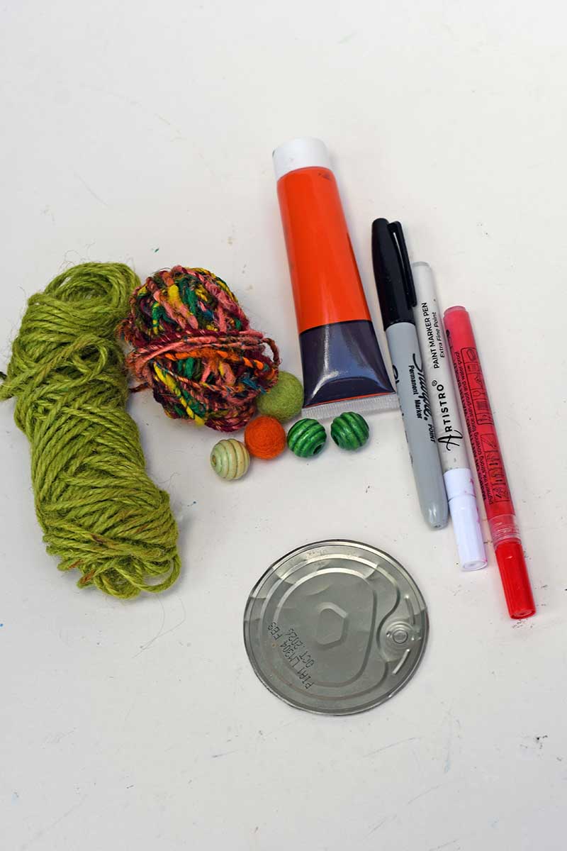 what you need to make spooky halloween tin can faces tin can lid, wool, acrylic paint pens and paint, plus beads
