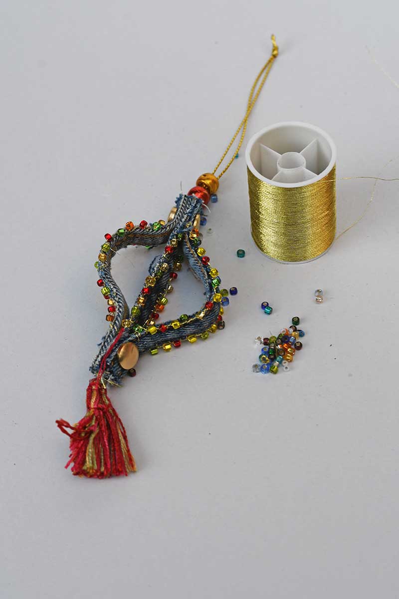 Adding seed beads to the seams of the denim ornaments