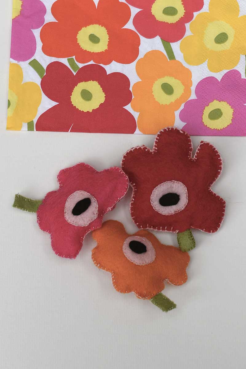All three Marimekko Unikko felt poppy brooches with Marimekko paper napkin