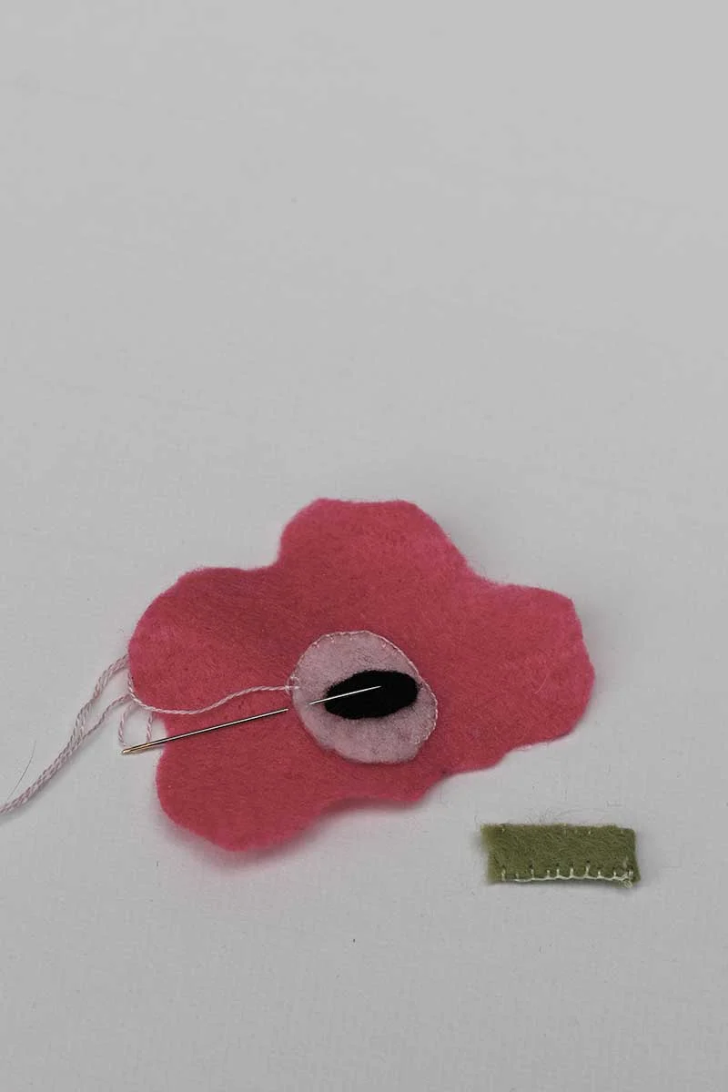 blanket stitching on the poppy center for DIY felt brooch