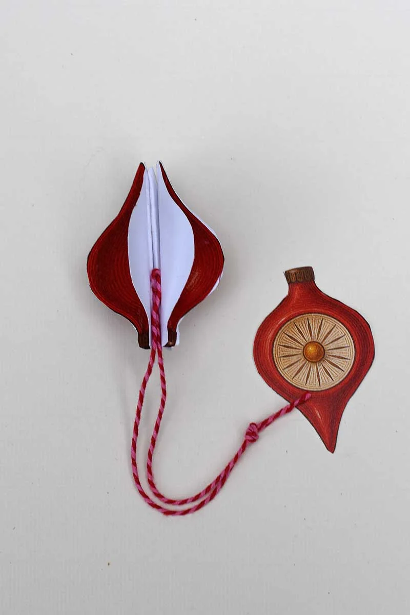 Gluing in the hanging twine before adding last piece of retro paper Christmas ornament.